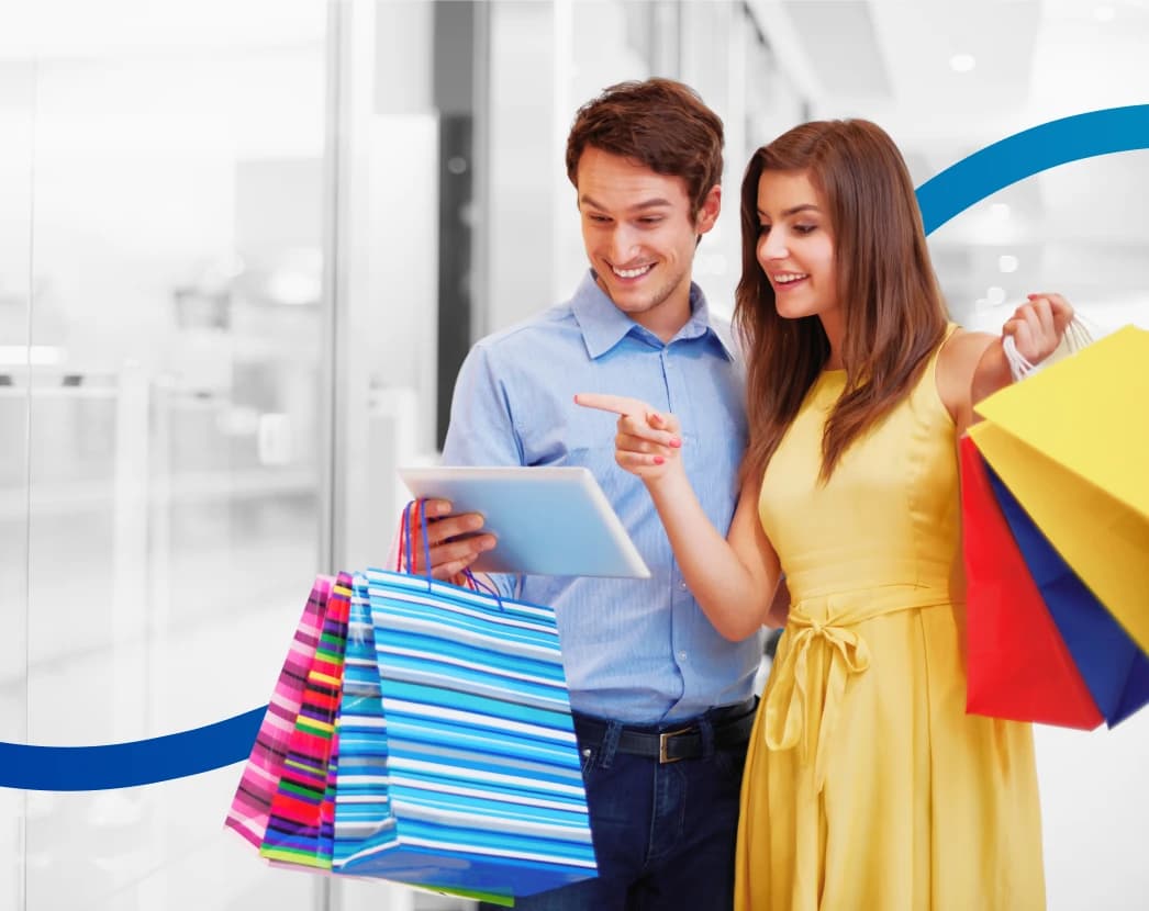 Man and woman with shopping bags browsing on a digital tablet